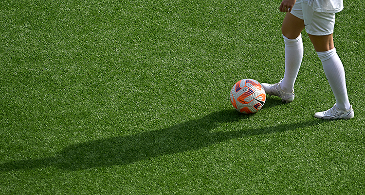 En kvinna med en boll på en fotbollsplan.