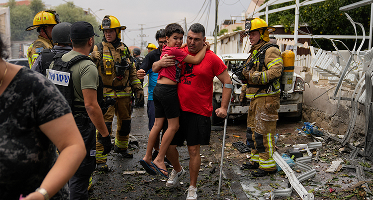 En man lyfter en pojke. Räddningsarbetare är runt dem. Foto: TT