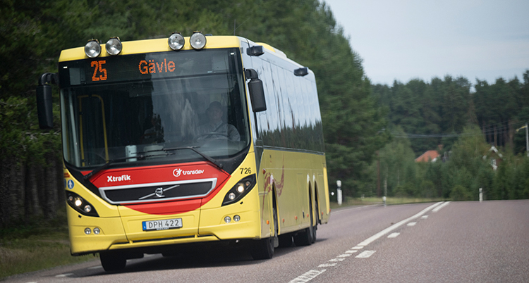 En gul buss åker på en väg. Det står Gävle på bussen.