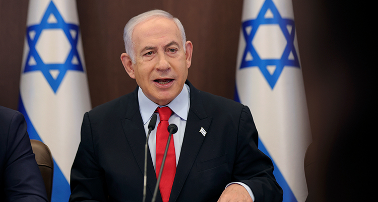 Netanyahu talar framför israeliska flaggor.