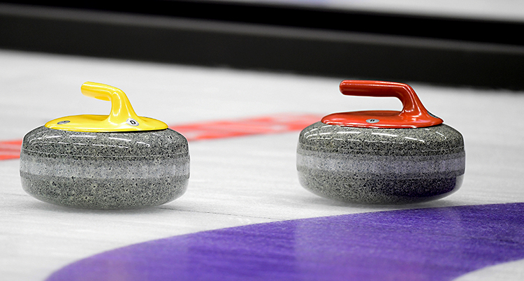 Två curlingstenar som ligger på isen.