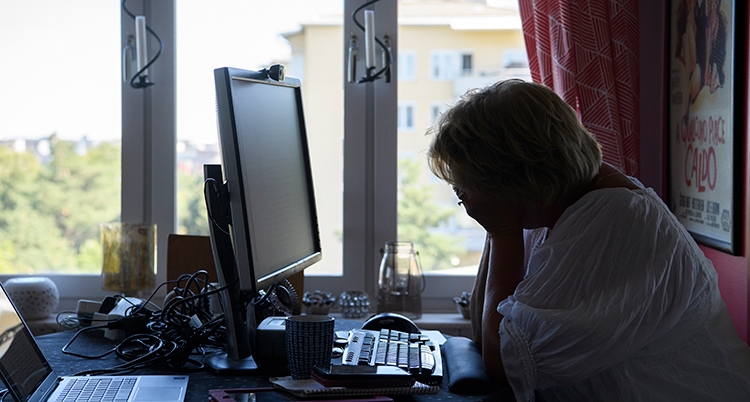 En trött kvinna framför en dator.