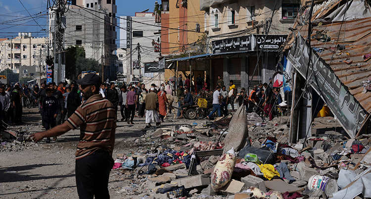människor framför ett bombat hus.