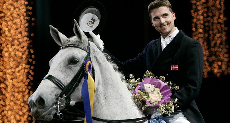 Helgstrand håller en bukett blommor medan han sitter på en häst och ser glad ut. Bilden är från ett tidigare tillfälle.