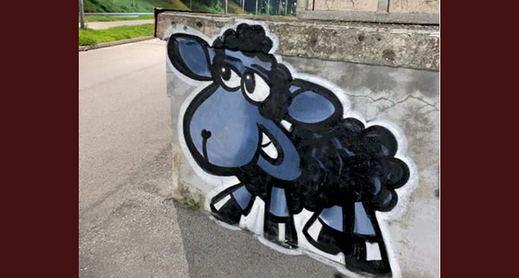 Ett stort lamm är målat på en mur av betong.