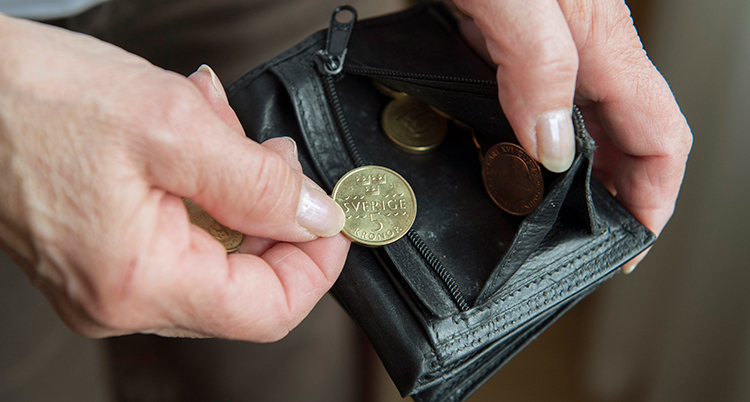 En person håller i en plånbok med några mynt i.