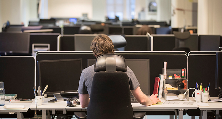 En man sitter och jobbar vid en dator på ett kontor.