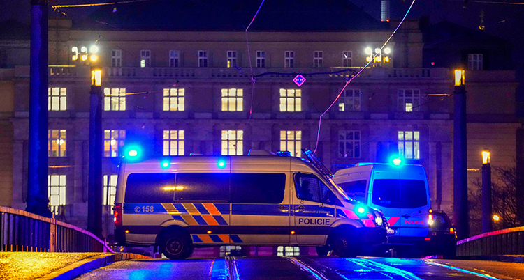 En polisbuss står framför ett stort hus på kvällen.