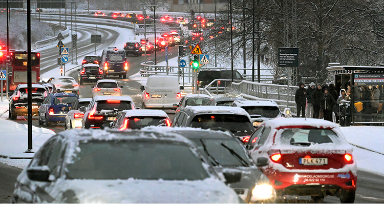 Snö och många bilar i kö på stor väg.