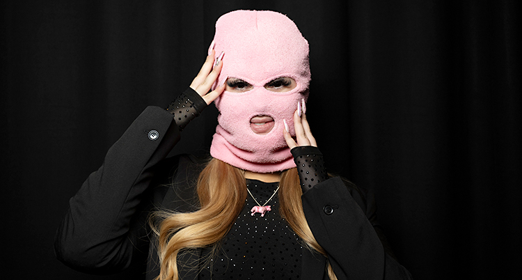 Hon har en rosa mask på huvudet. Man ser bara hennes ögon och mun.