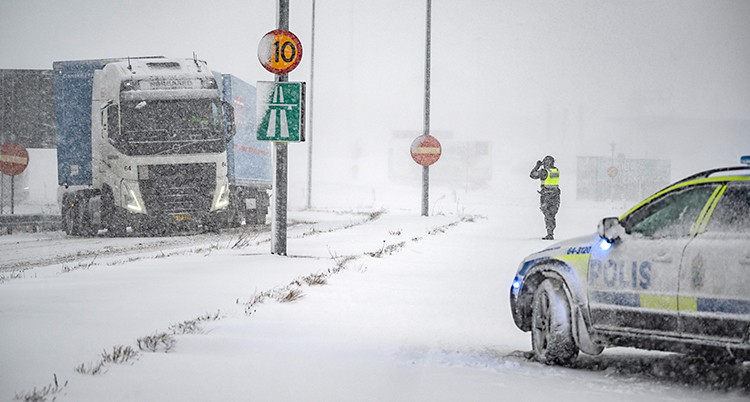 Det snöar och blåser. En lastbil har fastnat på vägen. Poliser är där.