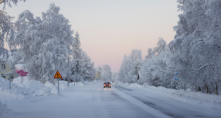 En bil på en vinterväg. Alla träd är vita av frost.