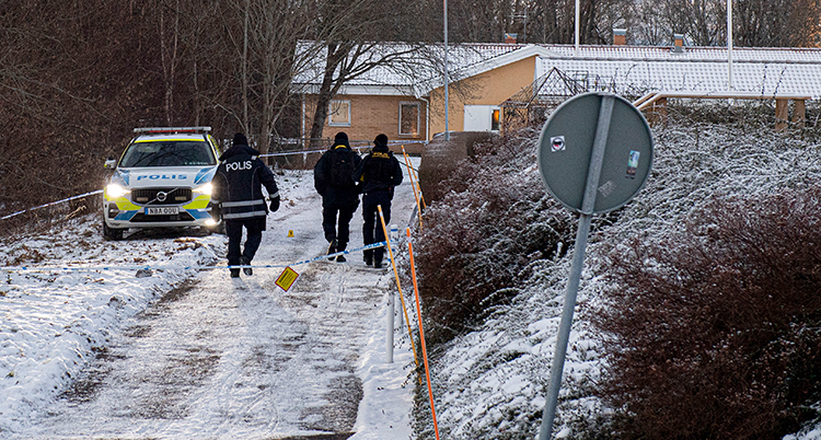 Tre poliser vid en polisbil på en liten väg.