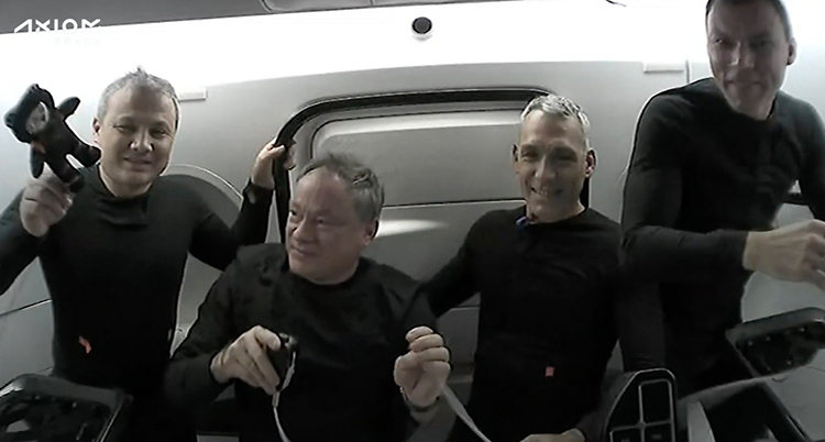 De tittar in i kameran. De har svarta kläder. De sitter bredvid varandra i raketen.