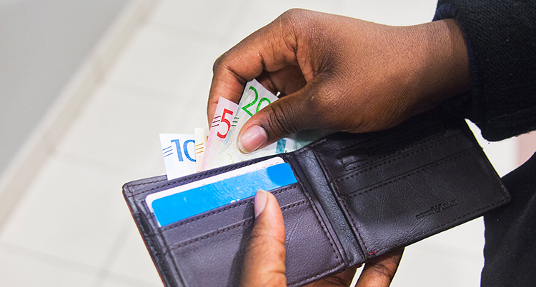 En person tar ut sedlar ur en plånbok.