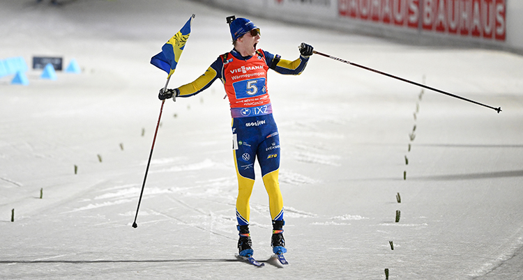 Han jublar när han åker i mål med en svensk flagga i ena handen.