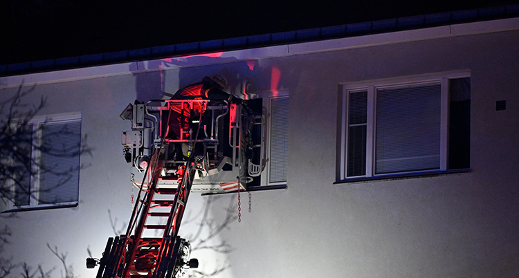 Räddningsarbetare står på en stege vid ett fönster.
