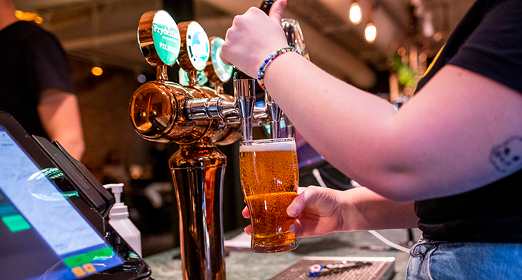 En person tappar upp öl på ett glas i en bar.