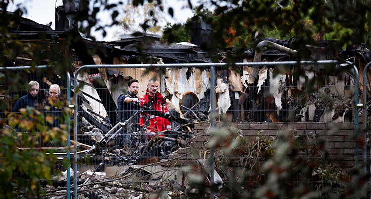 Räddningsarbetare står i resterna av det sprängda huset.