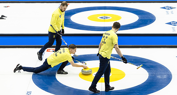 Från en match i curling. Tre svenska spelare syns på isen. En av dem skjuter iväg en sten.