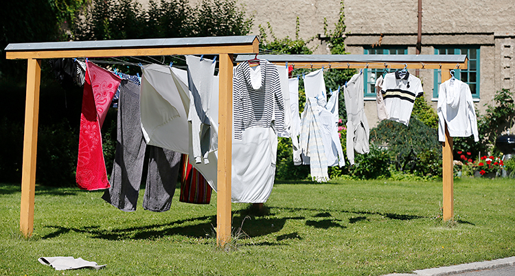 En solig dag. Tvättade kläder hänger på tork på en ställning utomhus.