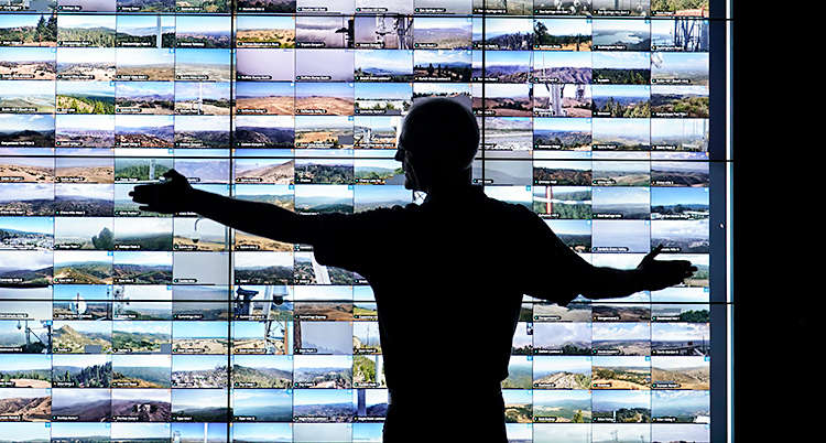 En man står framför en vägg med massa av videoskärmar.