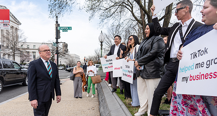 En bild från staden Washington i USA. En man i kostym står och pratar med demonstranter som har skyltar i händerna.