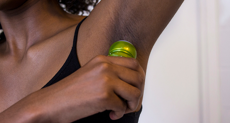 En person tar på deodorant under armen.