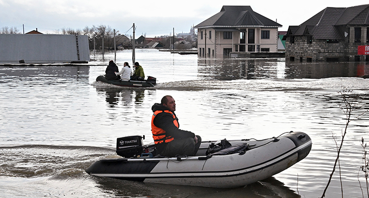 Två gummibåtar med folk i en översvämmad stad.