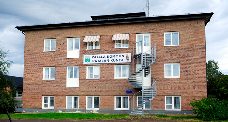 Ett hus i brunt tegel med en skylt där det står Pajala kommun på svenska och på meänkieli.