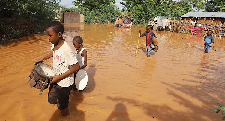 Några barn som vadar genom vatten. Deras by har blivit översvämmad.