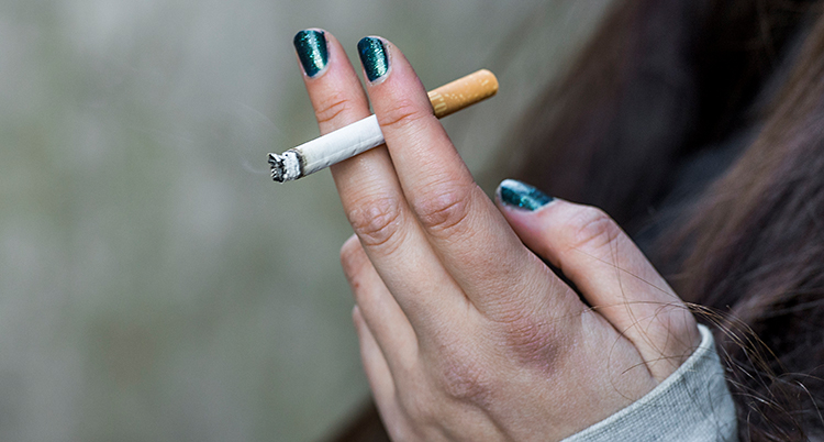 En närbild på en hand som håller i en cigarett.