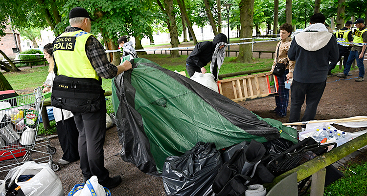 En park i staden Lund. En polis lyfter bort ett tält.