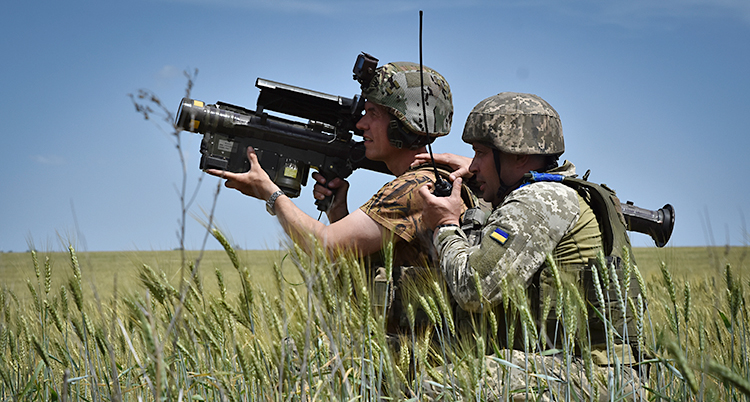 Två soldater står på ett fält och siktar med ett vapen.