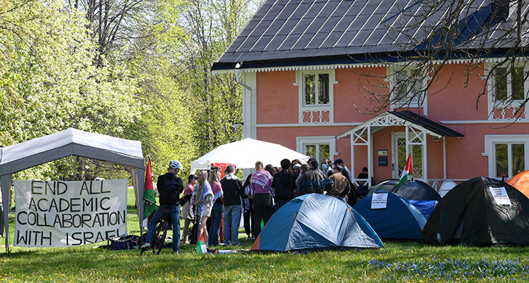 Människor och tält framför ett hus.