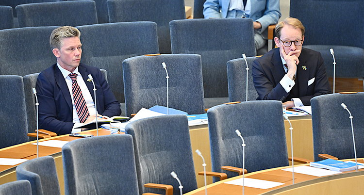 Pål Jonson och Tobias Billström sitter på varsin stol i riksdagens stora sal.