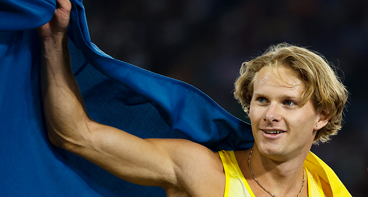 Han är glad, han håller en stor svensk flagga bakom ryggen.