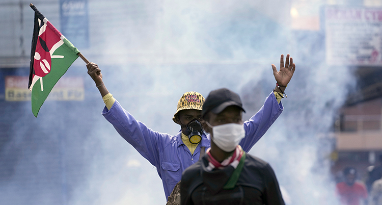 Två personer med masker för munnen. En håller upp en kenyansk flagga.