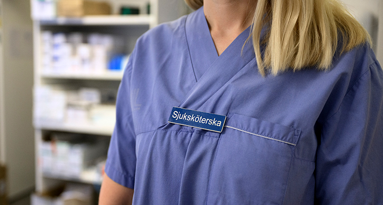 En person i blå skjorta. På skylten står det sjuksköterska.