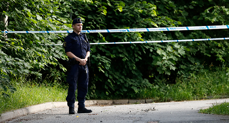 En polis framför ett band som spärrar av en väg.