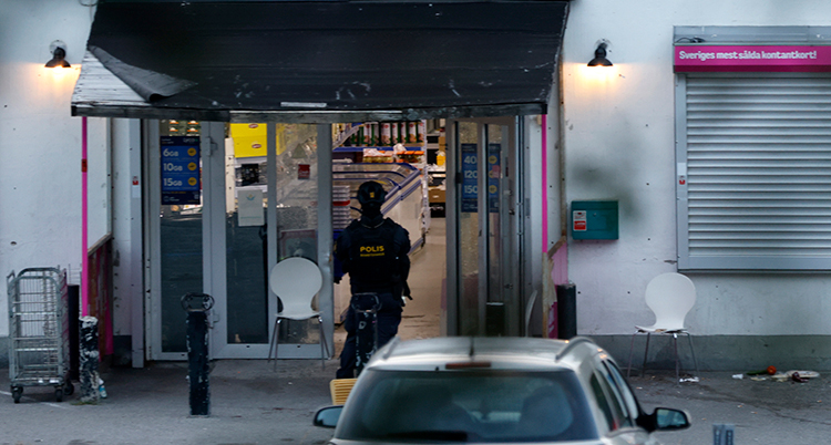 Poliser vid entrén till butiken som sprängdes.