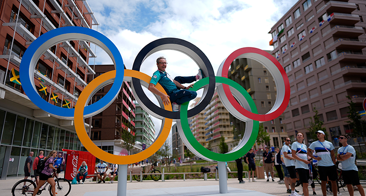 En man ligger på en skultur med de olympiska ringarna.