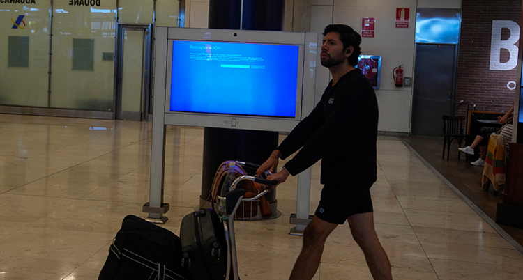 En man går förbi en datorskärm som inte fungerar på en flygplats.