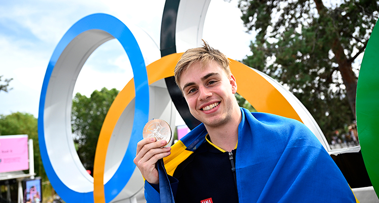 Han håller upp en rund medalj.