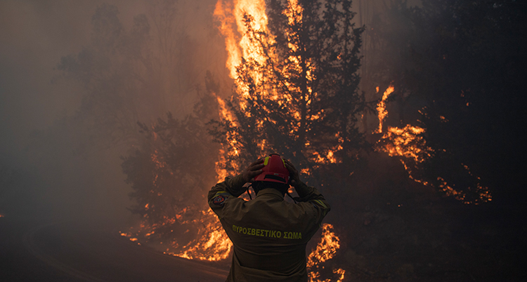 En brandman framför en stor brand i en skog.