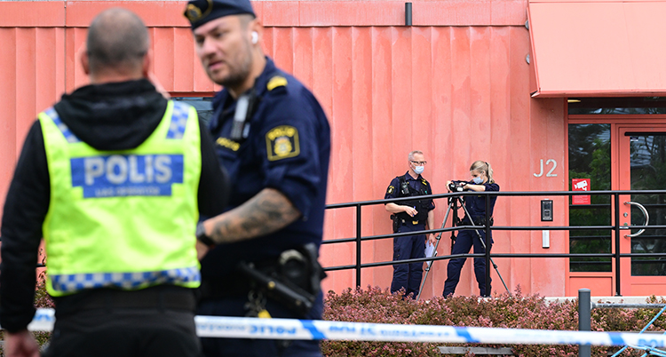 Poliser jobbar vid skolan som har en röd vägg.