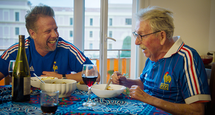 Filip och hans pappa Lars sitter vid ett bord och äter och pratar.