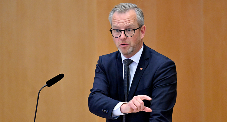 Han står i riksdagen och pratar i en mikrofon.