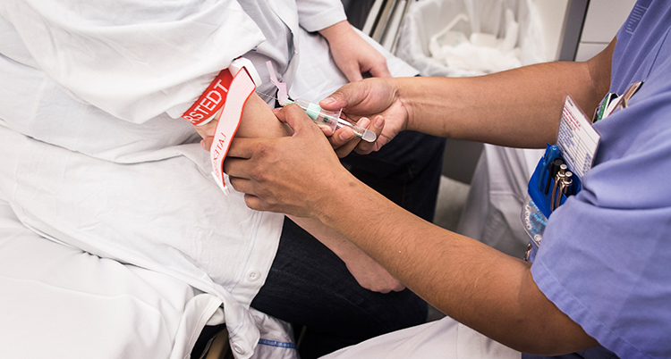 Manlig sjuksköterska tar blodprov på patient.