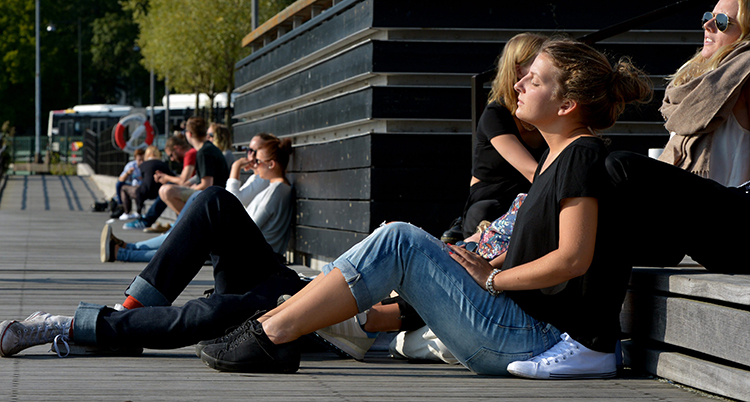 Några personer sitter och solar på ett trädäck.